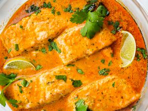 Microwave Red Curry Poached Salmon Topped with Cilantro and Lime Wedges in a Microwavable Glass Bowl