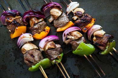Shish Kabobs on wooden skewers with onions, bell peppers, and mushrooms, ready to eat