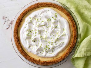 Overhead shot of a homemade keylime pie, covered with whipped cream and with a linen beside