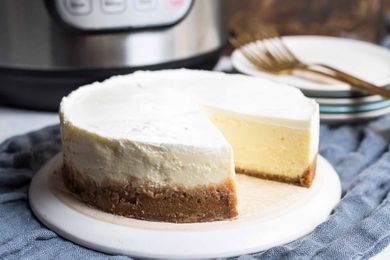 Cheesecake with a slice cut out sitting in front of an Instant pot