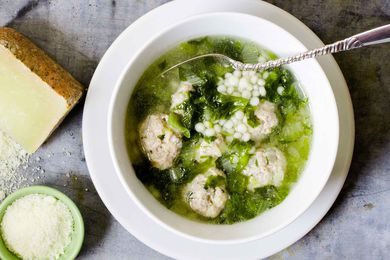 Italian wedding soup with meatballs in a white bowl and parmesan on the side