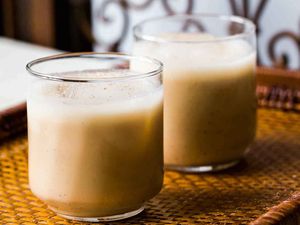 2 glasses of creamy Coquito on a woven mat