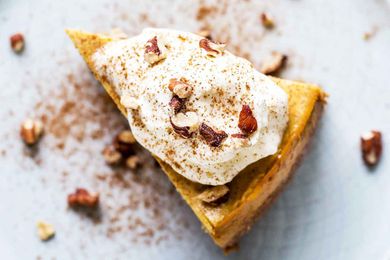 Pressure Cooker Pumpkin Cheesecake slice topped with whipped cream and nuts