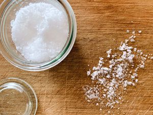 How to use sea salt flakes? Flaky sea salt shown in a small jar with some flakes on a counter.