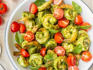 5-Ingredient Pesto Shrimp with Cherry Tomatoes in a Bowl Next to Cherry Tomatoes on a Vine