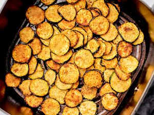 Air fried zucchini slices in the basket of an air fryer