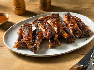 Barbecued baby back ribs cut up on a plate on a wooden table