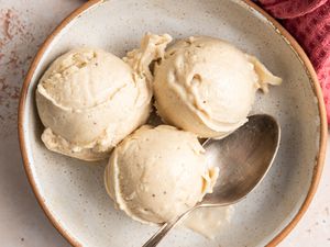 Three Scoops of Banana Nice Cream in a Bowl With a Spoon, and on the Counter, a Kitchen Towel