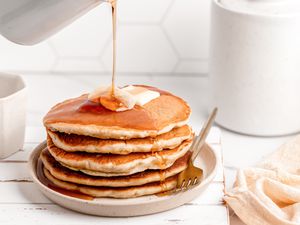 A stack of banana pancakes with syrup pouring over the top