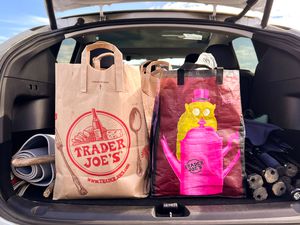 Trader Joe's shopping bags in the open trunk of a car