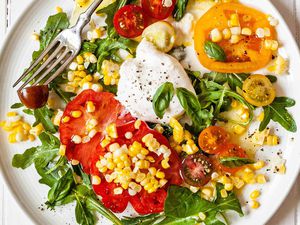 Plate of arugula salad with corn and tomatoes