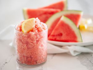 Side view of a watermelon granita with watermelon behind it
