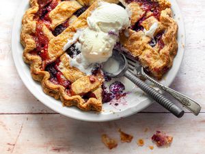 Blackberry Pie in a Pie Dish with a Slice Cut Out and Topped with Vanilla Ice Cream 