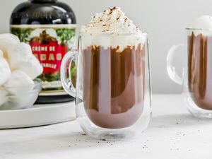 Boozy Hot Chocolate Topped with Whipped Cream and in the Background, a Bowl of Marshmallows and Creme Liqueur