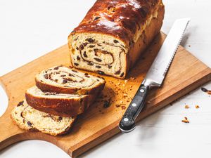 Slices of Cinnamon Swirl Raisin Brioche Loaf Next to the Remaining Loaf and a Bread Knife on a Cutting Board