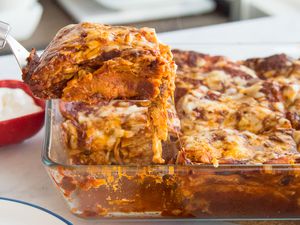 Cheesy chicken enchilada casserole, with a serving being lifted from the dish