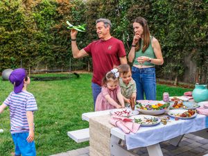 The Pfeffer parents and their three children play outside alongside a table of food