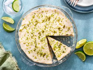 Lime icebox cake in a glass dish with one piece cut out and lime slices on the side