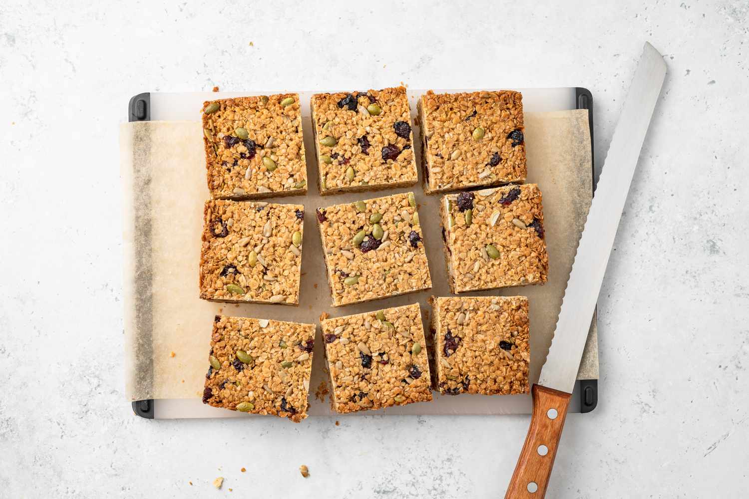 Sliced Flapjacks on a Parchment Paper Covered Cutting Board With a Bread Knife