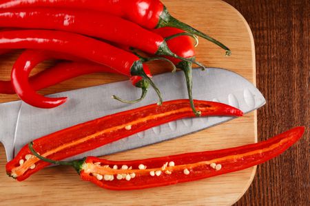 Hot red fresh red chiles on a cutting board, one sliced open