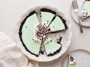 Overhead view of grasshopper pie cut into slices with one on a plate.
