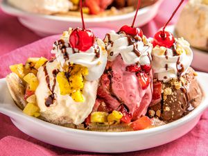 Grilled Banana Split Topped With Chocolate Sauce, Peanuts, Whipped Cream, and Three Maraschino Cherries in a Banana Split Dish