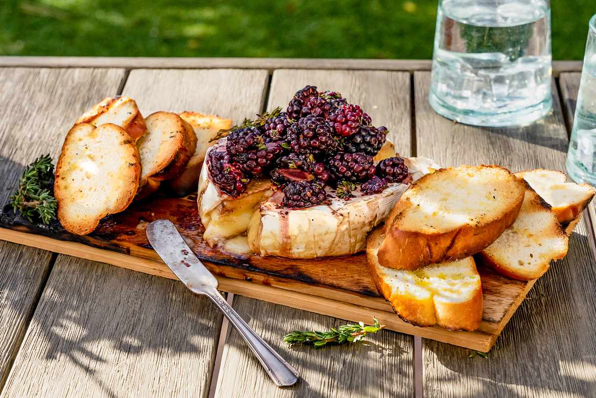 Grilled cedar plank brie, topped with blackberries and served on the plank with crostini