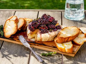 Grilled cedar plank brie, topped with blackberries and served on the plank with crostini
