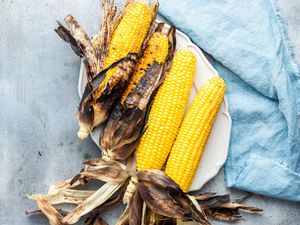 A Platter of Grilled Corn on the Cob with Husks Partially Removed