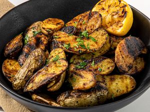 Grilled Fingerling Potatoes and a Grilled Halved Lemon in a Black Bowl 