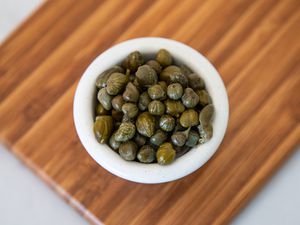 Small Bowl of Capers on a Wooden Board