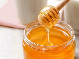 Honey jar with honey dripped from honey dipper