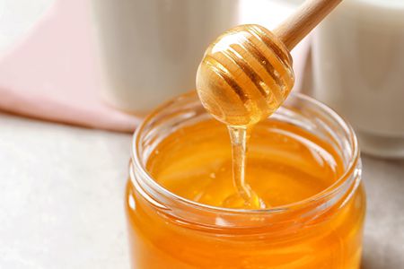 Honey jar with honey dripped from honey dipper
