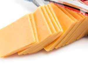 Slices of orange cheddar cheese coming out of an open package