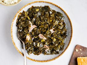 Instant Pot Collard Greens on a Plate with Serving Utensil Next to a Bowl of Mashed Potatoes and Cornbread