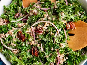 Bowl of Kale and Farro Salad with Spiced Candied Pecans with a Pair of Salad Servers
