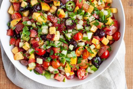 Bowl filled with stone fruit, tomato, and cucumber salad