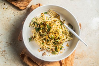 Lemony Sardine Pasta Topped With Toasted Breadcrumbs in a Bowl Sitting on a Mustard Colored Table Linen
