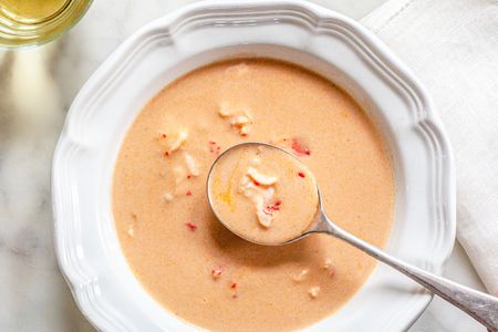 Bowl of Lobster Bisque with a Spoon Next to a Glass