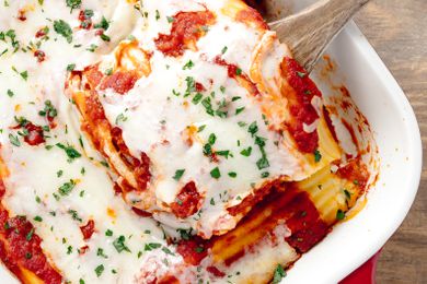 Manicotti Removed From Casserole Dish Filled With Manicotti Using a Wooden Spoon