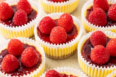 Mini Cheesecakes Wrapped in Cupcake Wrappers and Topped With Jam and Raspberries