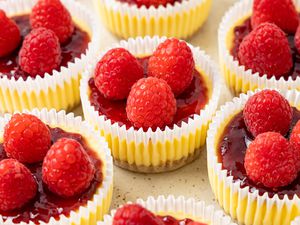 Mini Cheesecakes Wrapped in Cupcake Wrappers and Topped With Jam and Raspberries