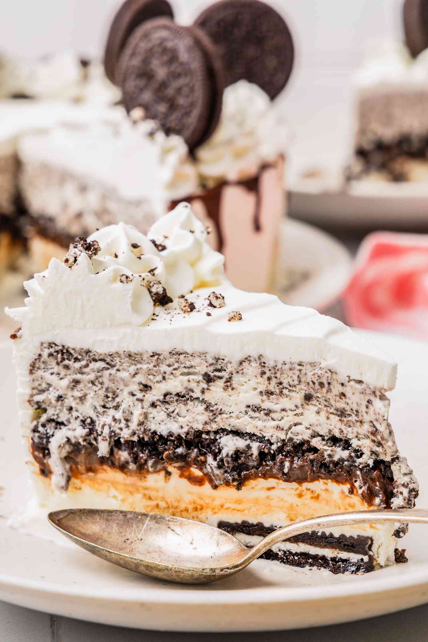 Slice of Oreo Ice Cream Cake on a Plate With a Spoon, and in the Surroundings, More Cake on a Plate, Another Slice on a Plate, and a Kitchen Towel