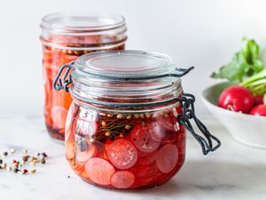 Quick Pickled Radishes in a Jar Next to a Bowl of Radishes