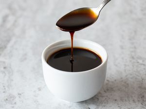 Pomegranate Molasses Drizzled from a Spoon to a Small Bowl with More Pomegranate Molasses