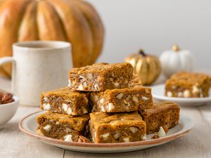 Pile of Pumpkin Blondies on a Plate with Fall Decor in the Background