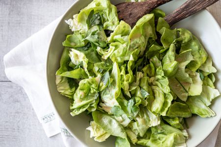 Bowl of Green Salad with Fresh Herbs and Red Wine Vinaigrette with Serving Utensils