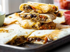 Stack of Loaded Sheet Pan Quesadillas Pieces on Sheet Pan with More Quesadilla Pieces 