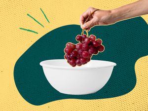 hand placing grapes in a bowl 