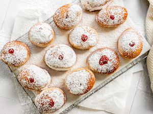 Sufganiyot (Israeli Jelly Donuts) on a Lined Cooling Rack Sitting on Parchment Paper and Next to a Knit Fabric 